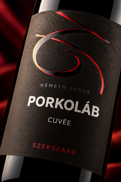 Close-up of a wine bottle label reading 'NÉMETH JÁNOS PORKOLÁB CUVÉE' with a dark textured background and red and gold abstract graphic accents.